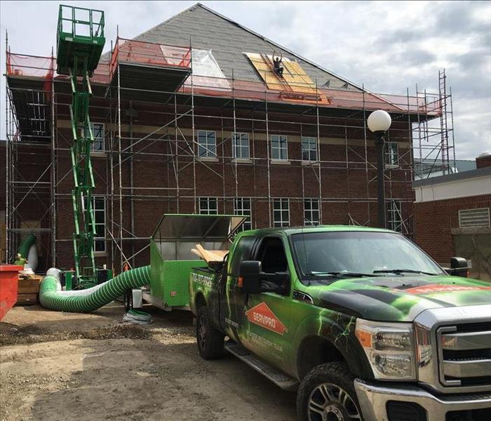 scaffolding jobsite with SERVPRO truck, worker on roof