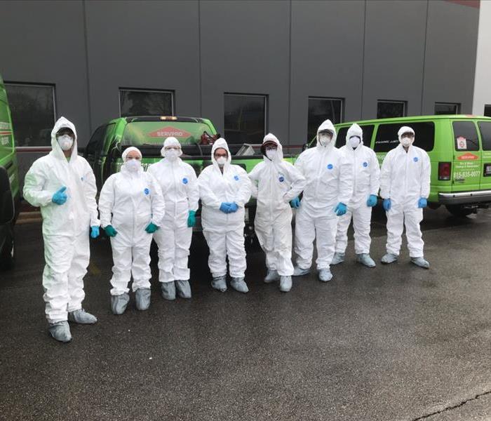 A group of cleaning technicians wearing PPE in front of a commercial building 