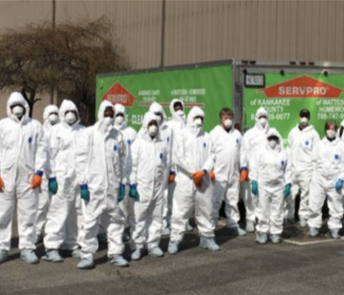 Group of SERVPRO technicians in full PPE in front of SERVPRO vehicles 